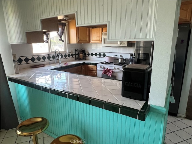 946 W Woodcrest, Bloomington, CA 92316 - kitchen with gas range gas stove, tile counters, decorative backsplash, and light tile patterned floors