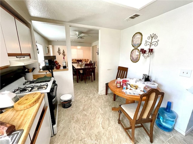 1325 Norton Ave, Dos Palos, CA 93620 - kitchen with gas range oven, a ceiling fan, range hood, and white cabinets