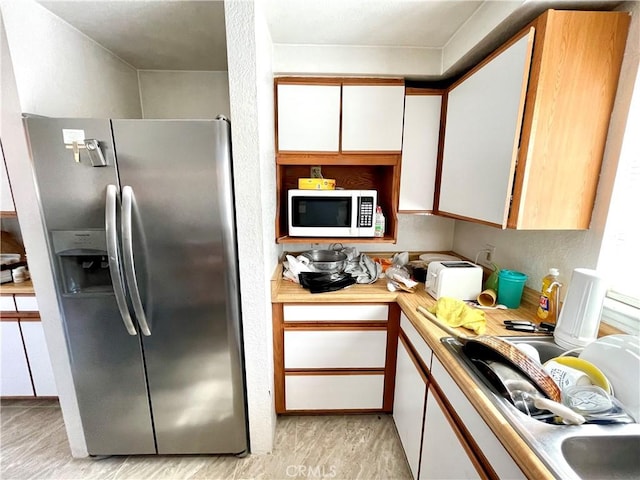 1325 Norton Ave, Dos Palos, CA 93620 - kitchen with stainless steel fridge with ice dispenser, white microwave, light wood-type flooring, and white cabinetry