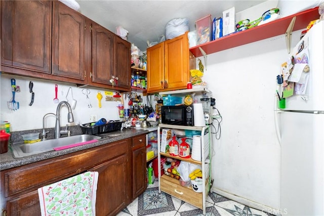 795 E 42nd Pl, Los Angeles, CA 90011 - kitchen with open shelves, dark countertops, freestanding refrigerator, light flooring, and brown cabinetry