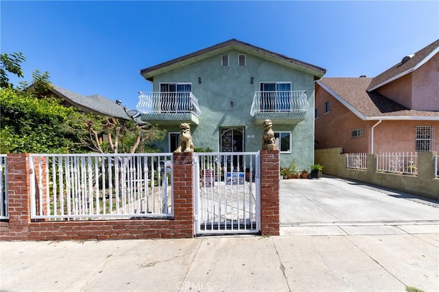 795 E 42nd Pl, Los Angeles, CA 90011 - view of front of home featuring a balcony, a fenced front yard, stucco siding, and a gate