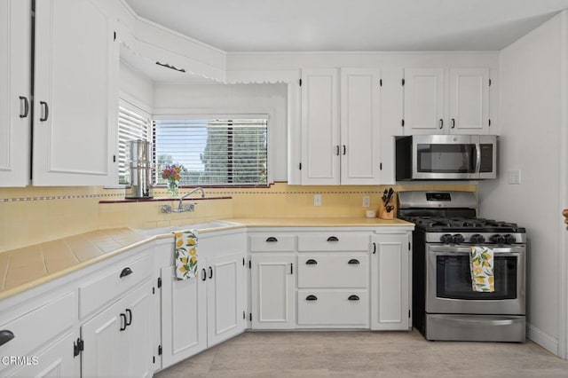 995 S La Luna Ave, Ojai, CA 93023 - kitchen with appliances with stainless steel finishes, tile countertops, white cabinets, and tasteful backsplash