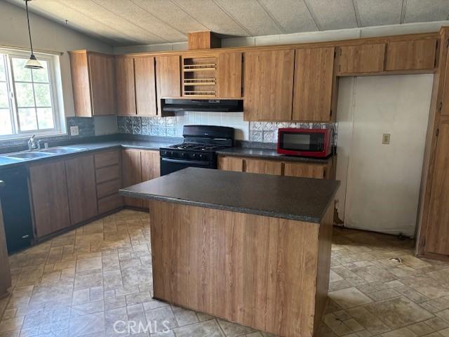 10220 Wrangler Way, Corona, CA 92883 - kitchen with black gas range, under cabinet range hood, dark countertops, brown cabinets, and light stone finish floors