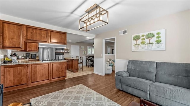 1052 Golden Rain St, Upland, CA 91786 - kitchen with under cabinet range hood, open floor plan, brown cabinets, a peninsula, and dark wood-style flooring