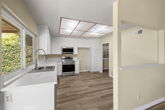 3262 Avenida Simi, Simi Valley, CA 93063 - kitchen with appliances with stainless steel finishes, white cabinetry, light wood-style floors, and light stone counters