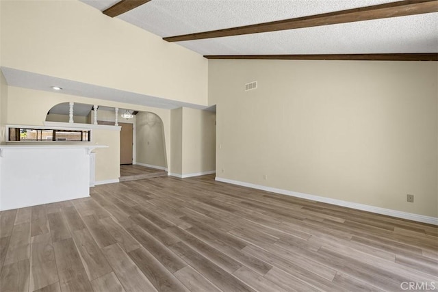 3262 Avenida Simi, Simi Valley, CA 93063 - unfurnished living room with arched walkways, beam ceiling, wood finished floors, high vaulted ceiling, and a textured ceiling