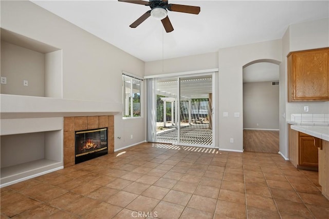 42730 Settlers Rdg, Murrieta, CA 92562 - unfurnished living room with ceiling fan, arched walkways, a tiled fireplace, and light tile patterned flooring