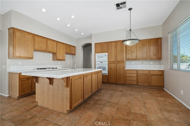 42730 Settlers Rdg, Murrieta, CA 92562 - kitchen with white appliances, tile counters, brown cabinets, recessed lighting, and arched walkways