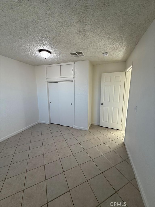 1032 W Coronado Ave, Ridgecrest, CA 93555 - unfurnished bedroom featuring light tile patterned floors, a textured ceiling, and a closet