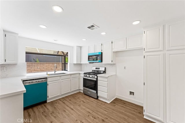 25632 Seaside Dr Unit 140, Dana Point, CA 92629 - kitchen with stainless steel appliances, decorative backsplash, white cabinetry, light wood finished floors, and light countertops