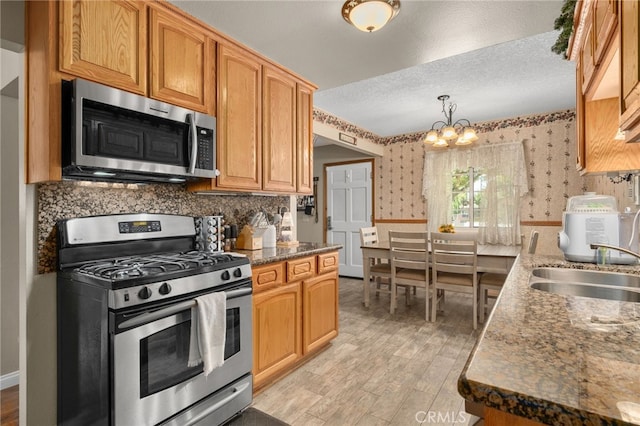 7420 London Ave, Rancho Cucamonga, CA 91730 - kitchen featuring appliances with stainless steel finishes, wallpapered walls, light wood-type flooring, a chandelier, and a textured ceiling