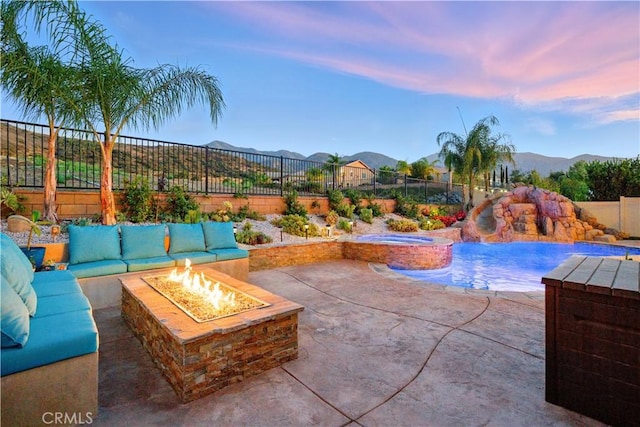 11905 Flicker Cv, Corona, CA 92883 - pool at dusk featuring a fenced backyard, a patio area, a mountain view, and a pool with connected hot tub