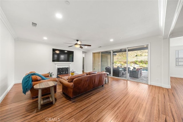11905 Flicker Cv, Corona, CA 92883 - living room featuring crown molding, a ceiling fan, light wood-style flooring, plenty of natural light, and a fireplace