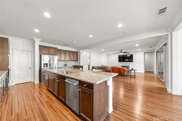 11905 Flicker Cv, Corona, CA 92883 - kitchen featuring appliances with stainless steel finishes, a center island with sink, light wood finished floors, open floor plan, and crown molding