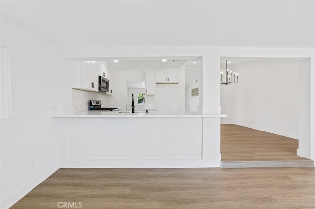 22959 Vought St, Moreno Valley, CA 92553 - kitchen featuring appliances with stainless steel finishes, a peninsula, a chandelier, light countertops, and white cabinetry