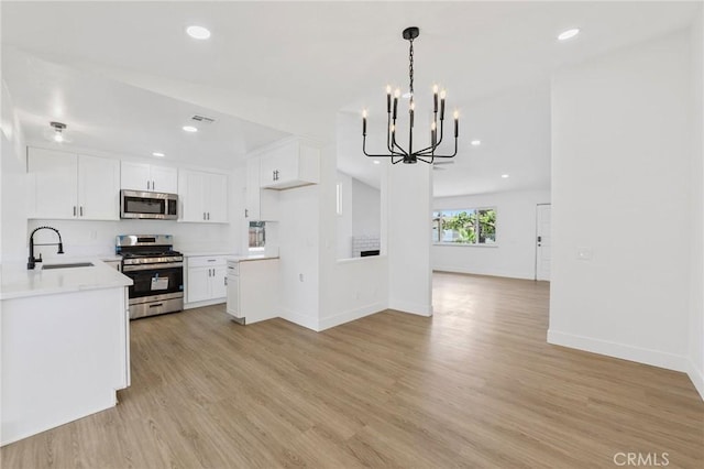 22959 Vought St, Moreno Valley, CA 92553 - kitchen with stainless steel appliances, open floor plan, a chandelier, light wood-type flooring, and light countertops