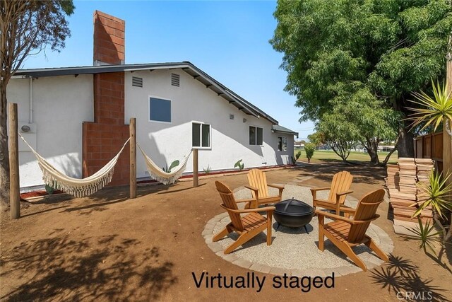 22959 Vought St, Moreno Valley, CA 92553 - back of house with an outdoor fire pit, a chimney, stucco siding, and a patio