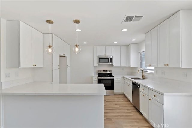 43000 Connecticut St, Palm Desert, CA 92211 - kitchen featuring stainless steel appliances, a peninsula, white cabinetry, light wood-style flooring, and hanging light fixtures