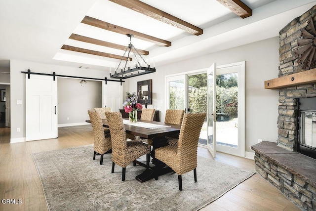 3041 Fairlea Rd, Santa Ynez, CA 93460 - dining area with a barn door, wood-type flooring, beamed ceiling, and a stone fireplace