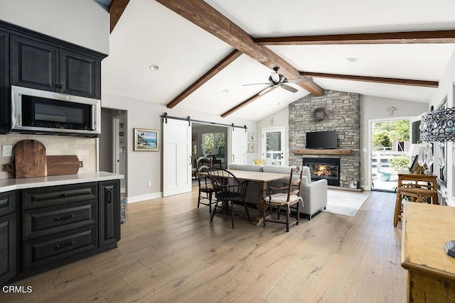 3041 Fairlea Rd, Santa Ynez, CA 93460 - dining area featuring a ceiling fan, a barn door, light wood finished floors, and a fireplace