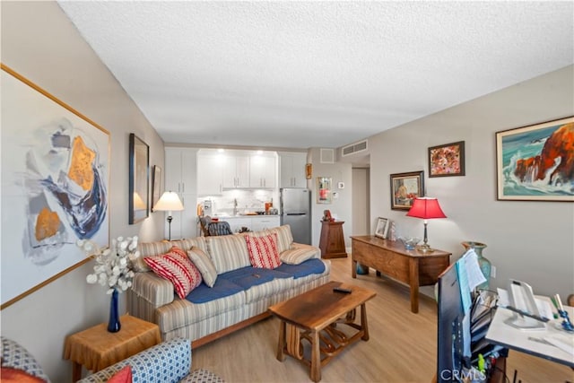 24055 W Paseo Del Lago Unit 753, Laguna Woods, CA 92637 - living area with light wood-style floors and a textured ceiling