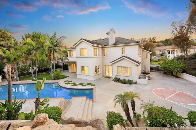 2832 Oak Knoll Dr, Diamond Bar, CA 91765 - back of property at dusk featuring a balcony, a patio, a chimney, stucco siding, and an outdoor pool
