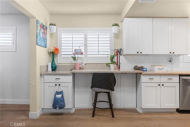 25211 Dana Ln, Moreno Valley, CA 92551 - kitchen with light wood finished floors, white cabinetry, decorative backsplash, light countertops, and stainless steel dishwasher