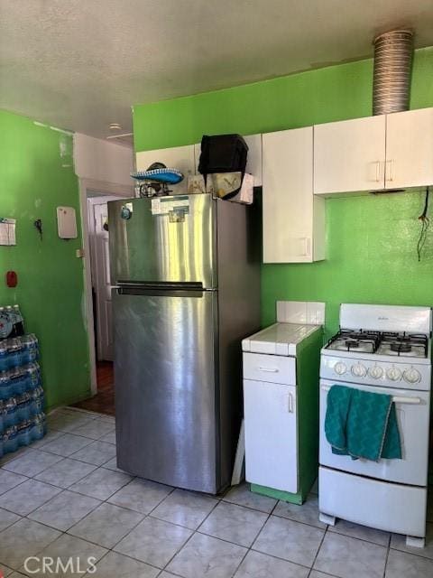 711 N Crane Ave, Compton, CA 90221 - kitchen with white gas range, freestanding refrigerator, tile countertops, white cabinets, and light tile patterned floors