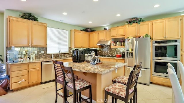 2056 Mission Hills Dr, Oxnard, CA 93036 - kitchen featuring appliances with stainless steel finishes, under cabinet range hood, light brown cabinetry, a center island, and tasteful backsplash
