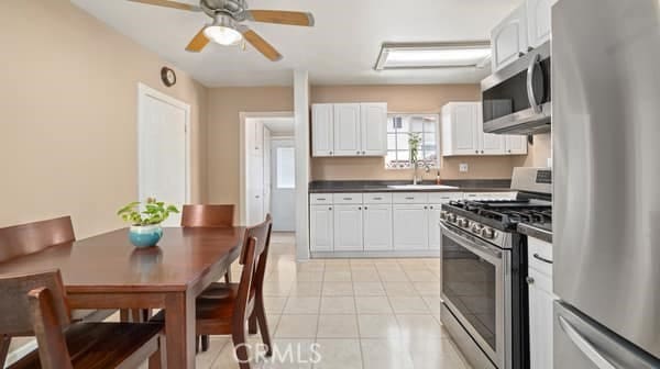 1724 S Vecino Ave, Glendora, CA 91740 - kitchen with stainless steel appliances, dark countertops, white cabinets, light tile patterned flooring, and ceiling fan