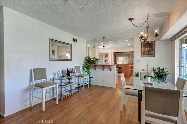 12108 Muriel Dr, Lynwood, CA 90262 - dining space with light wood finished floors, a textured ceiling, and a chandelier