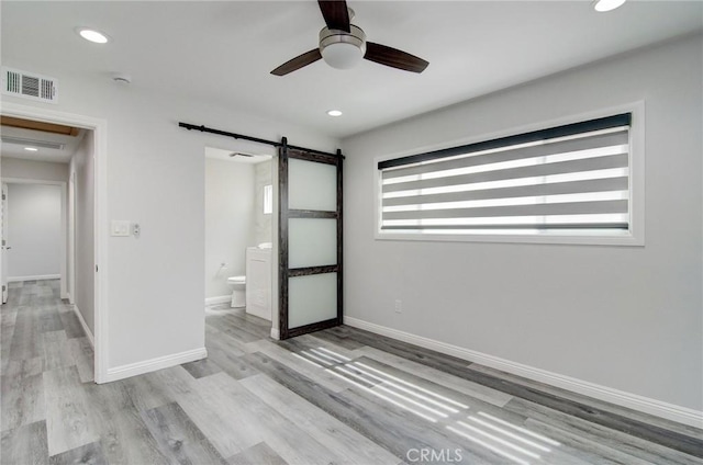 12517 Walcroft St, Lakewood, CA 90715 - unfurnished bedroom with a barn door, wood finished floors, recessed lighting, connected bathroom, and ceiling fan