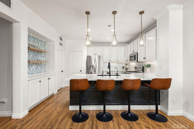 5 Duxbury St, Ladera Ranch, CA 92694 - kitchen with stainless steel appliances, a peninsula, wood finished floors, a kitchen breakfast bar, and ornamental molding