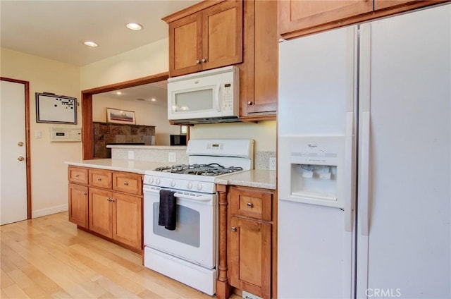 1251 Hackett Ave, Long Beach, CA 90815 - kitchen with white appliances, light wood-type flooring, light countertops, recessed lighting, and brown cabinets