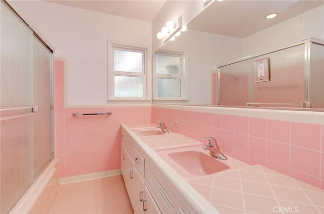 1251 Hackett Ave, Long Beach, CA 90815 - bathroom with double vanity, tile patterned floors, combined bath / shower with glass door, tile walls, and a wainscoted wall