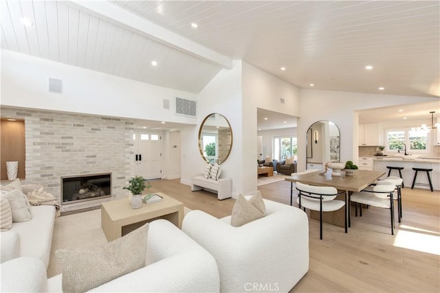 19281 Sierra Inez Rd, Irvine, CA 92603 - living room featuring light wood-type flooring, a fireplace, recessed lighting, beam ceiling, and arched walkways
