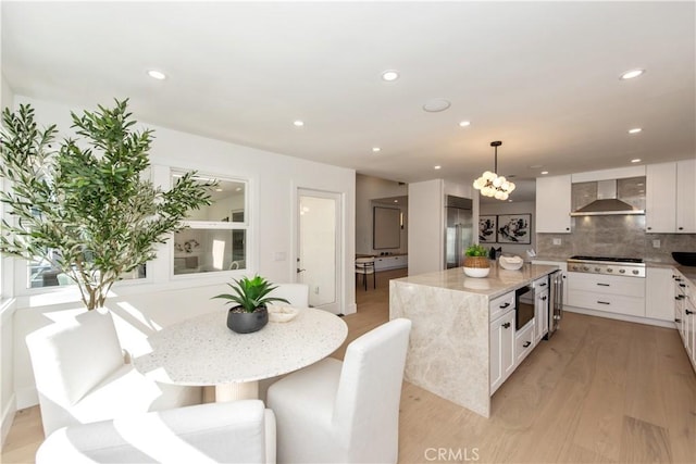 19281 Sierra Inez Rd, Irvine, CA 92603 - kitchen featuring built in appliances, wall chimney range hood, tasteful backsplash, light wood finished floors, and white cabinets