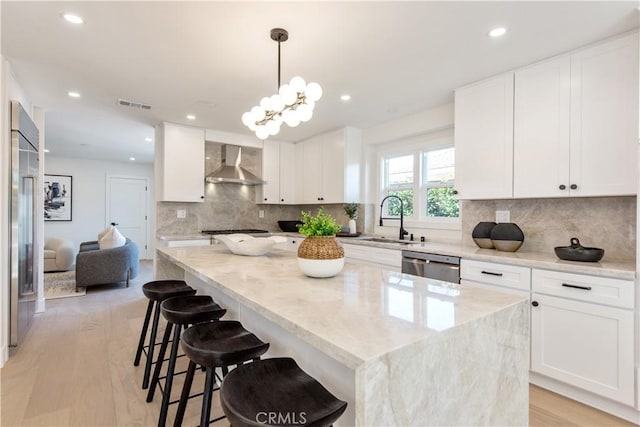 19281 Sierra Inez Rd, Irvine, CA 92603 - kitchen featuring appliances with stainless steel finishes, wall chimney exhaust hood, a kitchen island, light stone counters, and tasteful backsplash