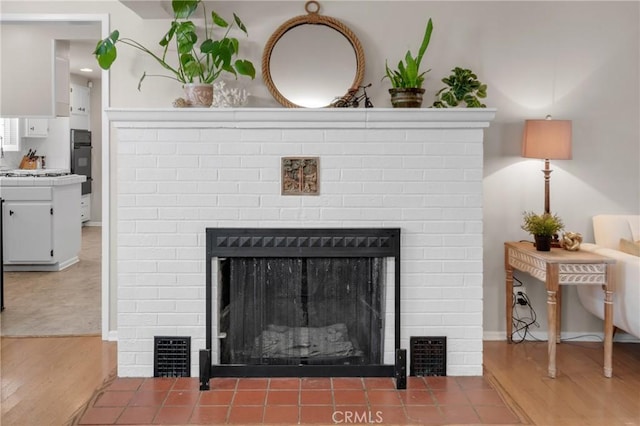 1269 W 1st St, San Pedro, CA 90732 - detailed view of a brick fireplace, wood finished floors, gas stovetop, and black oven