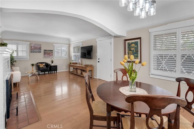 1269 W 1st St, San Pedro, CA 90732 - dining space with a brick fireplace, light wood-type flooring, arched walkways, and a chandelier