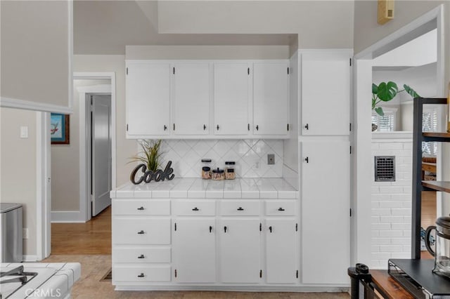 1269 W 1st St, San Pedro, CA 90732 - kitchen with tile counters, white cabinetry, and backsplash