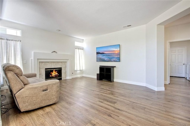 32197 Callesito Fadrique, Temecula, CA 92592 - living room featuring a tiled fireplace, light wood-style flooring, and plenty of natural light