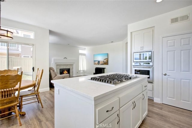 32197 Callesito Fadrique, Temecula, CA 92592 - kitchen with appliances with stainless steel finishes, a kitchen island, light wood-style flooring, white cabinetry, and recessed lighting