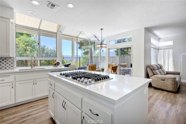 32197 Callesito Fadrique, Temecula, CA 92592 - kitchen featuring stainless steel gas stovetop, light wood-style floors, white cabinets, light countertops, and open floor plan