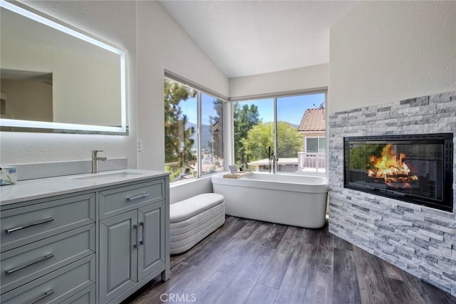 32197 Callesito Fadrique, Temecula, CA 92592 - bathroom with vaulted ceiling, a freestanding tub, vanity, wood finished floors, and a fireplace