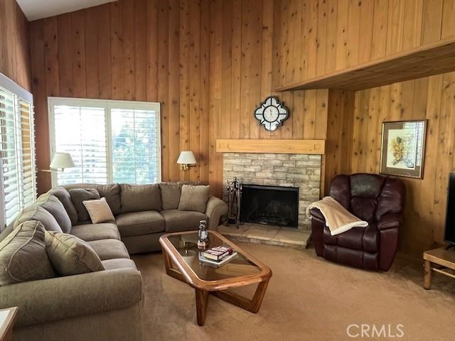 27821 Peninsula Dr, Lake Arrowhead, CA 92352 - living room featuring wooden walls, a stone fireplace, and carpet flooring