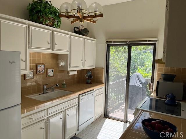 27821 Peninsula Dr, Lake Arrowhead, CA 92352 - kitchen with white appliances, white cabinets, tasteful backsplash, tile counters, and a chandelier