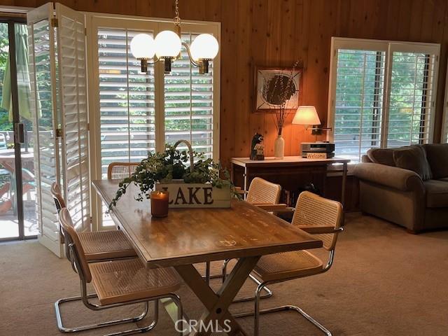 27821 Peninsula Dr, Lake Arrowhead, CA 92352 - carpeted dining area with wooden walls and a chandelier