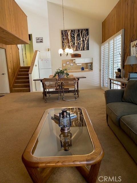 27821 Peninsula Dr, Lake Arrowhead, CA 92352 - carpeted living room with vaulted ceiling, stairway, and a chandelier