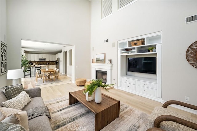 29125 Starwood Pl, Saugus, CA 91390 - living room featuring a high ceiling, light wood-style floors, and a fireplace with raised hearth